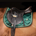Green saddle pad with gold cord trim, modelled on chestnut horse, on a black background.