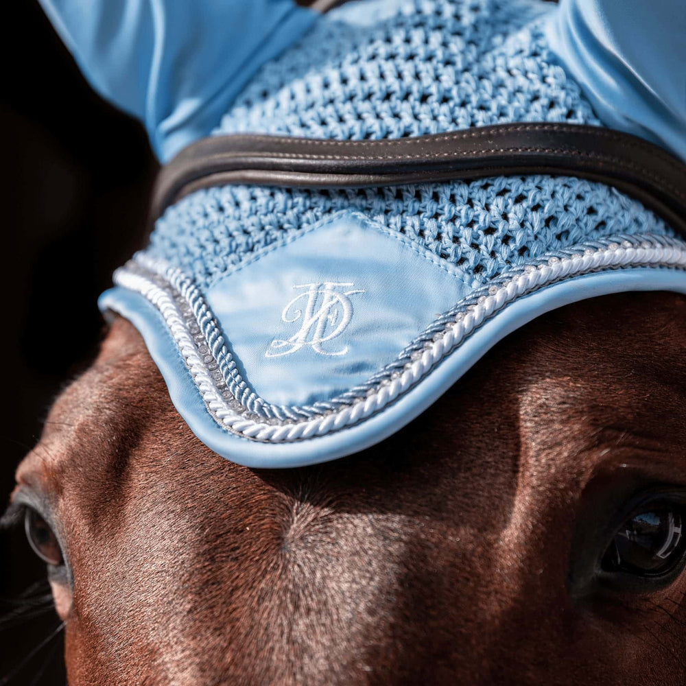 Light blue fly veil with matching blue, white and diamante trim, modelled on a bay horse, on a black background.