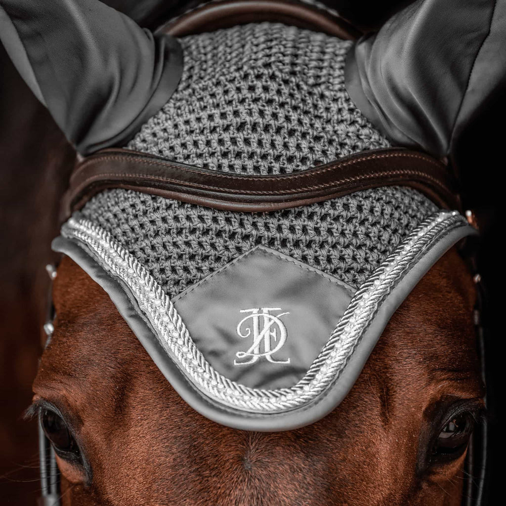 Close up of grey fly veil with silver and diamante trim, modelled on a bay horse, on a black background.