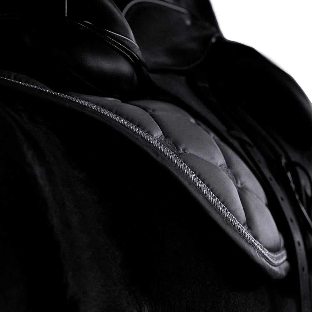 Close up of grey saddle pad with silver and diamante trim, modelled on a black horse with a dressage saddle.